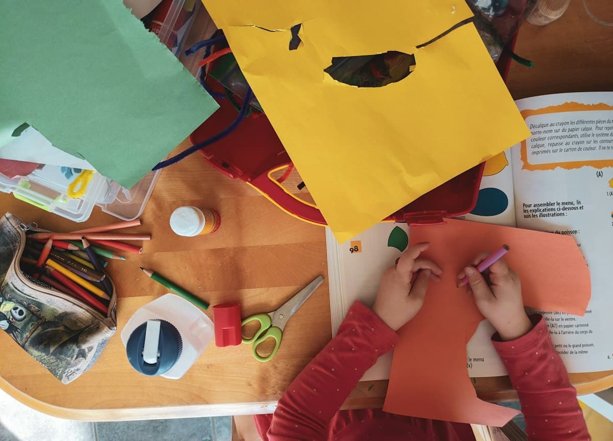 Child cutting and gluing colored paper